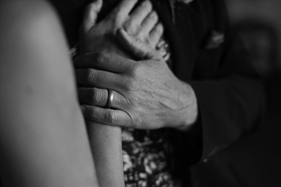 Two hands held together with a wedding ring
